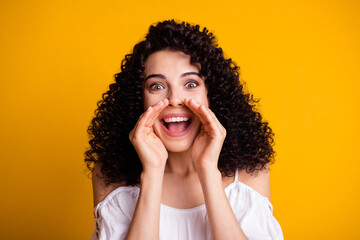 Photo portrait of curly brunette shouting loudly news hand near mouth isolated on vivid yellow...