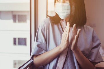 Asian woman patient applauding to support people fighting coronavirus covid-19 near hospital window