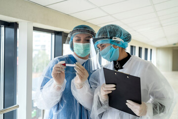 Fototapeta na wymiar healthcare workers in protective mask, face shield and gloves write rezult test patient