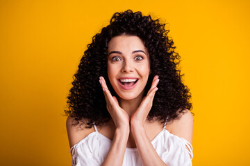 Fototapeta na wymiar Photo portrait of cheerful surprised girl keeping hands near cheeks smiling isolated on vivid yellow color background