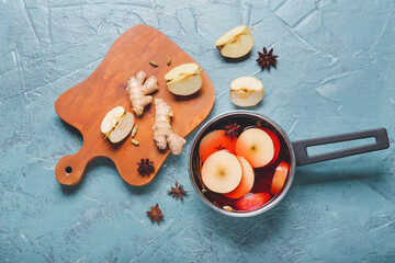 Saucepan with hot mulled wine on color background
