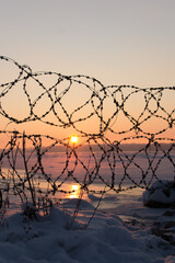 winter landscape frozen river Volga at dusk of sunset. frozen barbed wire with icicles. Soft focus