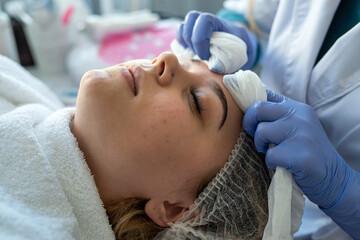 Obraz na płótnie Canvas Cosmetologist preparing face to the procedure of young woman lying on a table in a beauty clinic