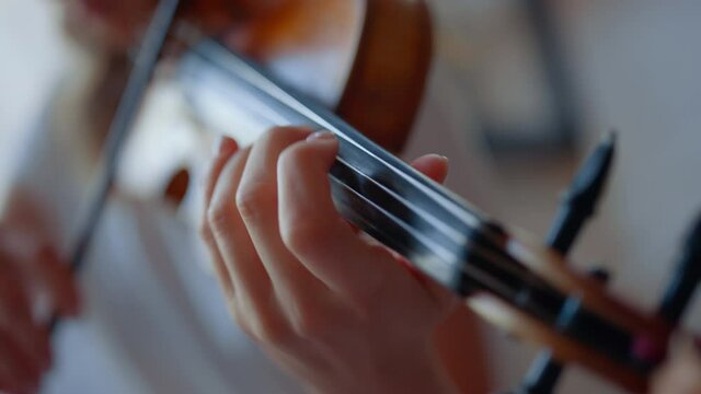 Teenage girl hand playing violin. Woman fingers pressing strings on violin