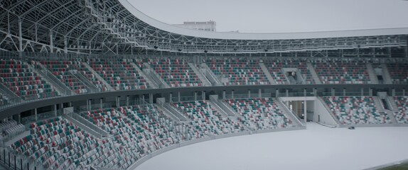 Empty outdoor football soccer stadium seats covered with snow in winter, light snowfall. Shot with 2x anamorphic lens