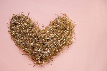 Love and relationship concept. Valentine's Day.Heart of gold tinsel on a light pink background. The...