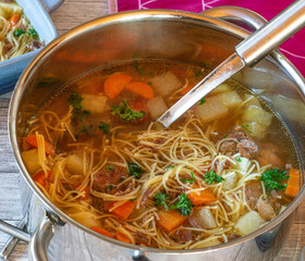Pot with chicken soup and ladle