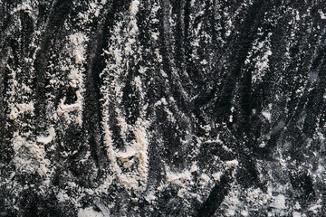 Black culinary background. Bakery desk. Dark table with flour powder spreading copy space.
