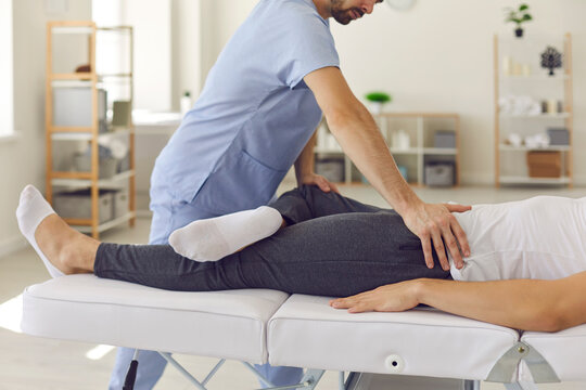 Confident man professional doctor osteopath fixing man patinets legs in position to fix joints