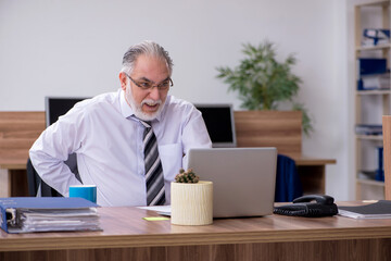 Old male employee suffering from radiculitis at workplace
