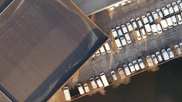 Aerial top down view of parking lot filled with white Postal Delivery Service Van Truck vehicles