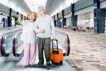 Elderly couple carrying luggage at airport terminal