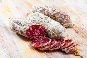 Italian cacciatori salami sausages cut in slices on a wooden desk, closeup. High quality photo