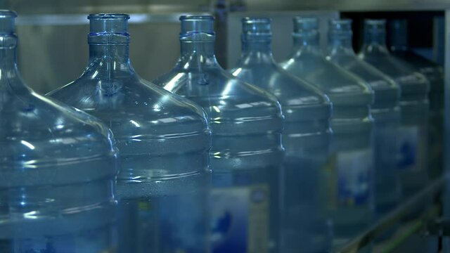 Cooler water bottles in row on factory conveyor