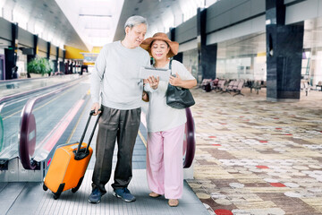 Senior couple using a tablet at airport terminal
