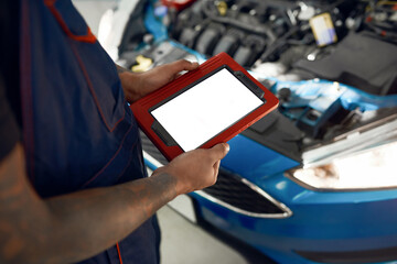 Tablet screen in mechanic hands on open hood background