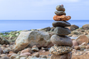 Rest and seaside vacation. Stones pyramid on the seashore at sunny day. Pebble beach, beautiful view. Concept of balanced life, harmony and relax.