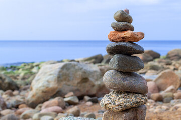 Fototapeta na wymiar Rest and seaside vacation. Stones pyramid on the seashore at sunny day. Pebble beach, beautiful view. Concept of balanced life, harmony and relax.