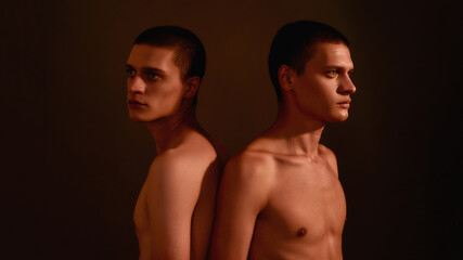 Fototapeta na wymiar Close relatives. Portrait of two young half naked men, caucasian twin brothers standing back to back isolated over brown background in studio