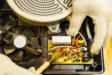 Electric stove service. Hands in white gloves with a brush remove dust from the electric stove.
