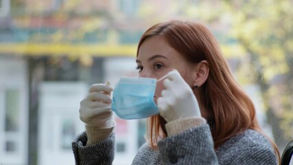 pandemic trip, female passenger wearing gloves puts medical mask on her face while traveling in public transport, precautionary measures