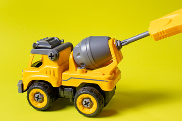 The toy typewriter is a concrete mixer and screwdriver that twists the cog on a yellow background....