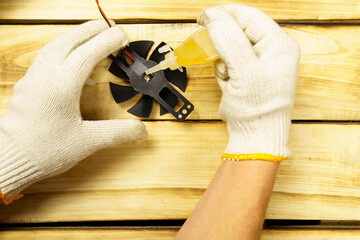 The foreman greases the electric stove screw with oil on a wooden background.