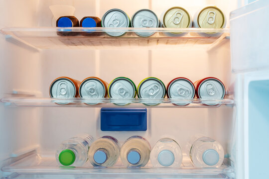 Colorful Soft drink cans and cold soda or mineral water inside the fridge in hotel room.