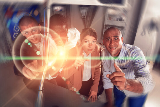 Multiracial people trying to find solution of conundrum in escape room with special light effects