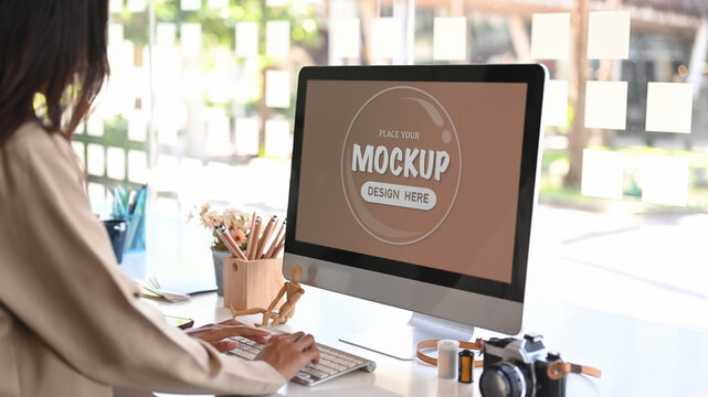 Side view of female designer working on computer in office. Blank screen for graphics display montage.