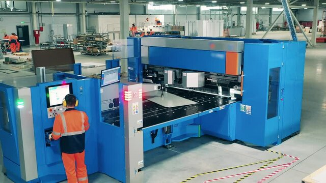 Laborer working with industrial equipment. Factory operator is working with a modern cutting machine