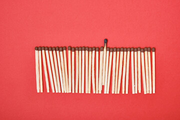 matches in a row on a red background, one burned-out match among the new