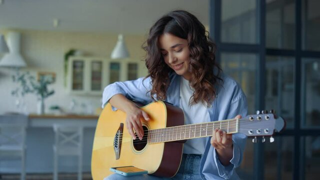 Girl playing guitar. Female guitarist recording guitar sound on mobile phone