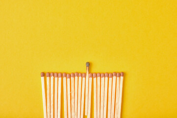 new matches and one burnt one are laid out in a row on a yellow background