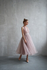 Sexy Fashion beautiful woman in dress is standing against the wall. Perfect makeup, romantic...