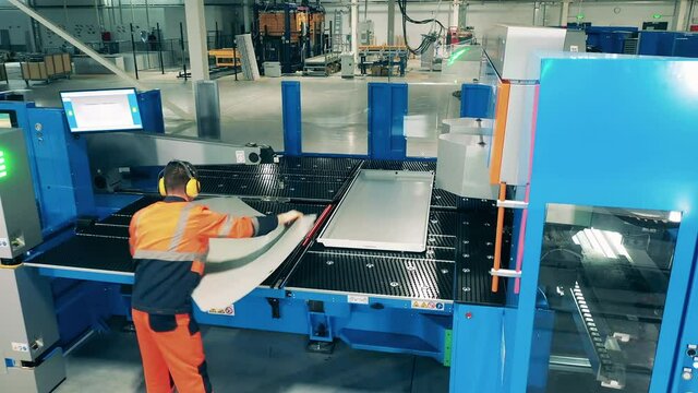 Laborer working with industrial equipment. Operator is putting aluminum plate onto the factory machine