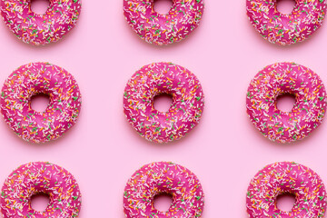 Sweet pink donut with multicolored sprinkles on a pink background flat lay pattern