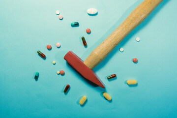Pills and hammer on the blue background
