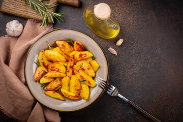 Roasted potatoes with garlic, olive oil and rosemary.  Ingredients. Vegan food. Top view, dark...