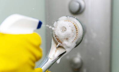 Close-up spray of cleaning agent onto the shower head. Lime deposits on the tap.
