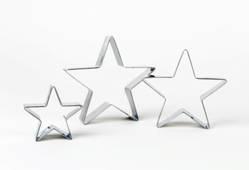Three metal cookie cutters in the shape of a star of different sizes on a white background. Family concept - mom, dad and child.