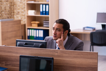 Young male employee unhappy with excessive work in the office