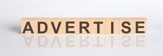 ADVERTISE word from wooden blocks on white desk