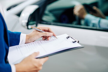 Dealership manager filling customer information when customer test driving car before buying it