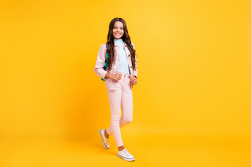 Full length photo of charming joyful schoolgirl wear rucksack good mood isolated on yellow color background