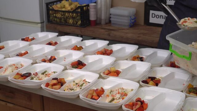 Volunteer packs free Christmas dinners in meal prep containers.  Holiday basket of groceries. Charities, churches, community soup kitchens, and restaurants serve a meal to a poor and needy