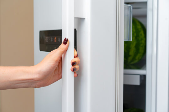 Female Hand Opens Door Of A Fridge