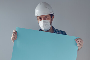 Construction engineer with white safety helmet and protective mask holding blank paper poster as copy space