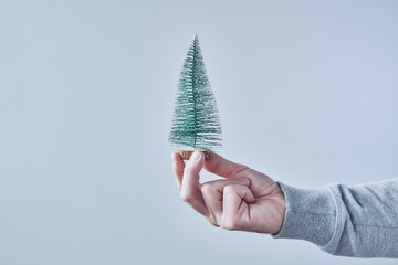 Hand holding small artificial fir tree for Christmas holiday season