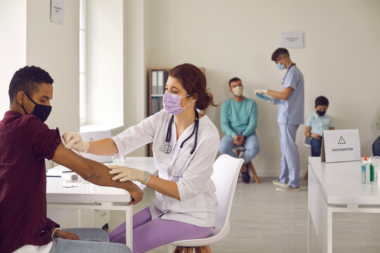 Professional nurse giving an antiviral injection to a young African-American man